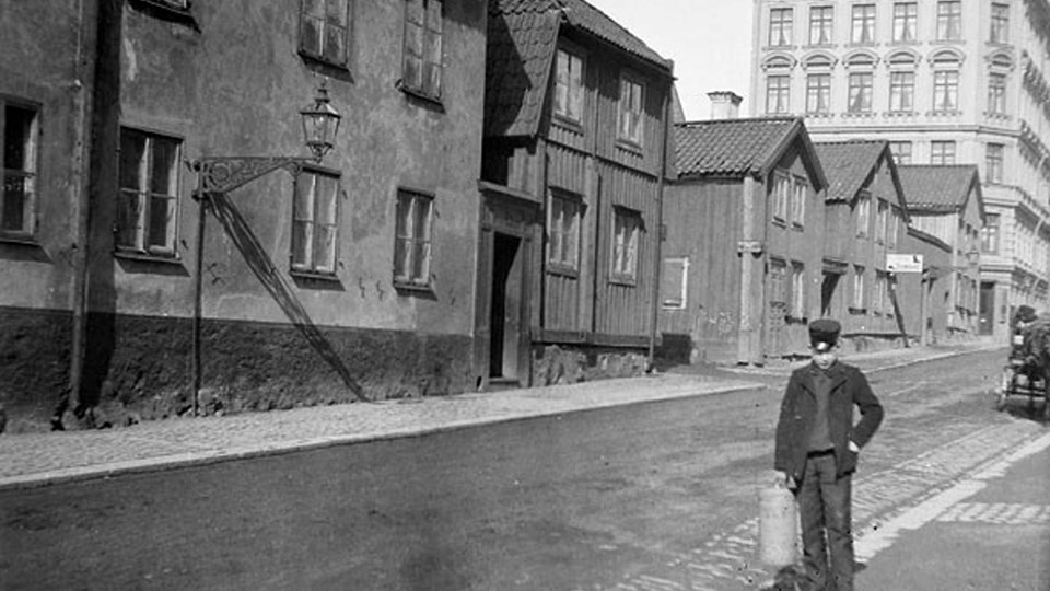 Foto på en pojke som står på en gata i stadsmiljö sent 1800-tal. 