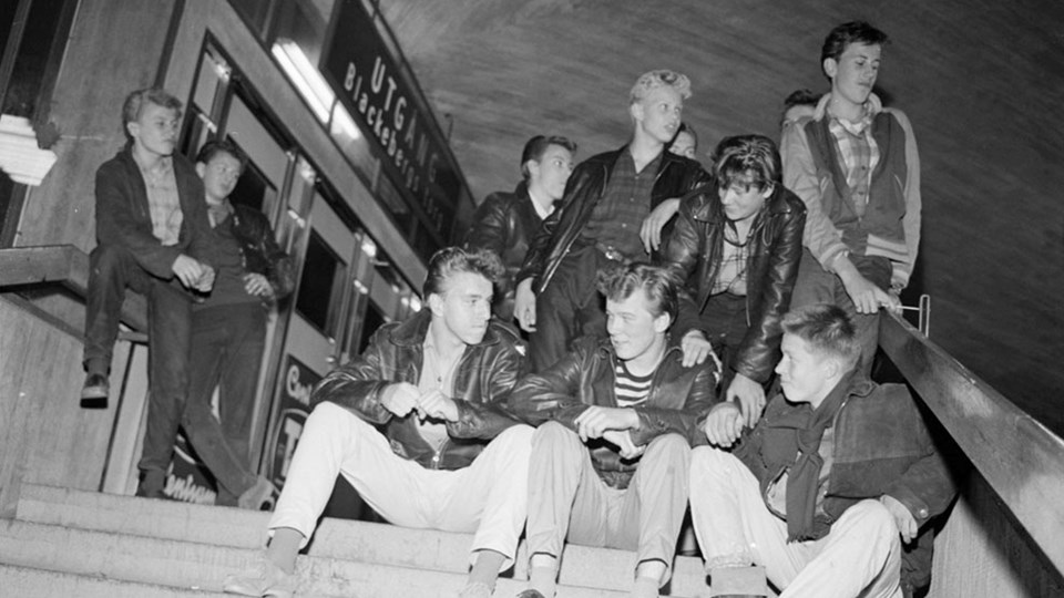 Ungdomar sitter i en trappa  utanför tunnelbanestation på 1950-talet. Foto.