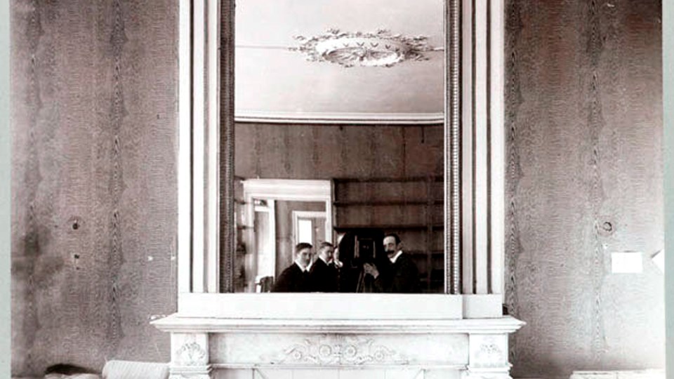Foto av tre män som fotograferar en spegel i ett större rum.