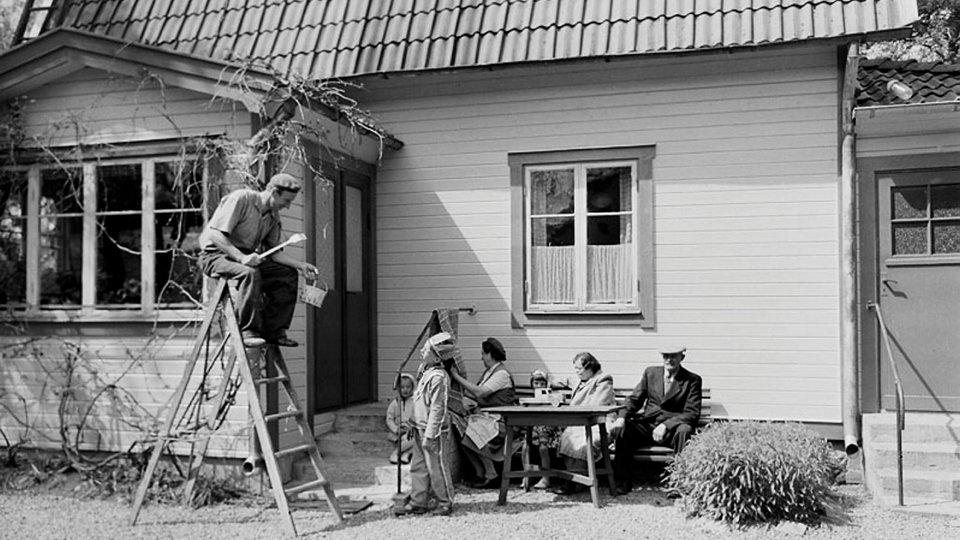 En familj sitter ute i sin trädgård.