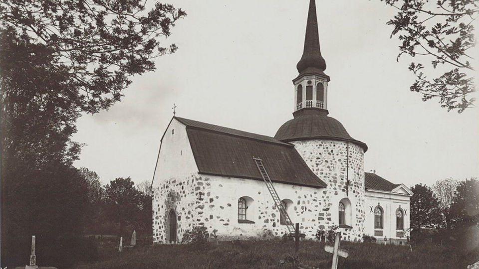 Vit kyrka med gravkors runt omkring.
