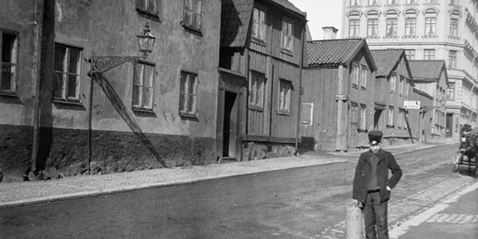 Foto på en pojke som står på en gata i stadsmiljö sent 1800-tal. 