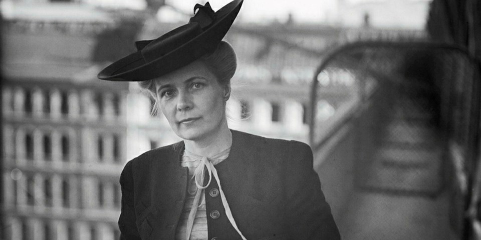 Kvinna på takterass iförd hatt. Foto.