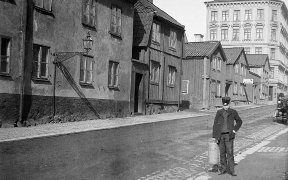 Foto på en pojke som står på en gata i stadsmiljö sent 1800-tal. 