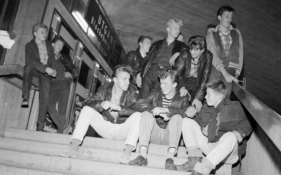 Ungdomar sitter i en trappa  utanför tunnelbanestation på 1950-talet. Foto.