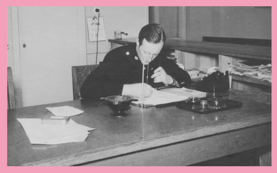 En polis läser en utredning vid ett bord. Foto.