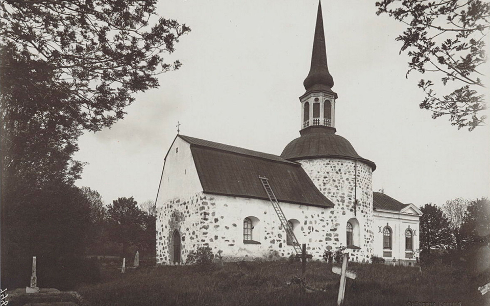 Vit kyrka med gravkors runt omkring.