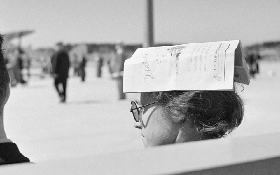 Foto av en kvinna med tidningen på huvudet.