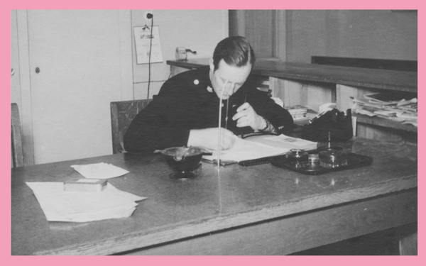 En polis läser en utredning vid ett bord. Foto.